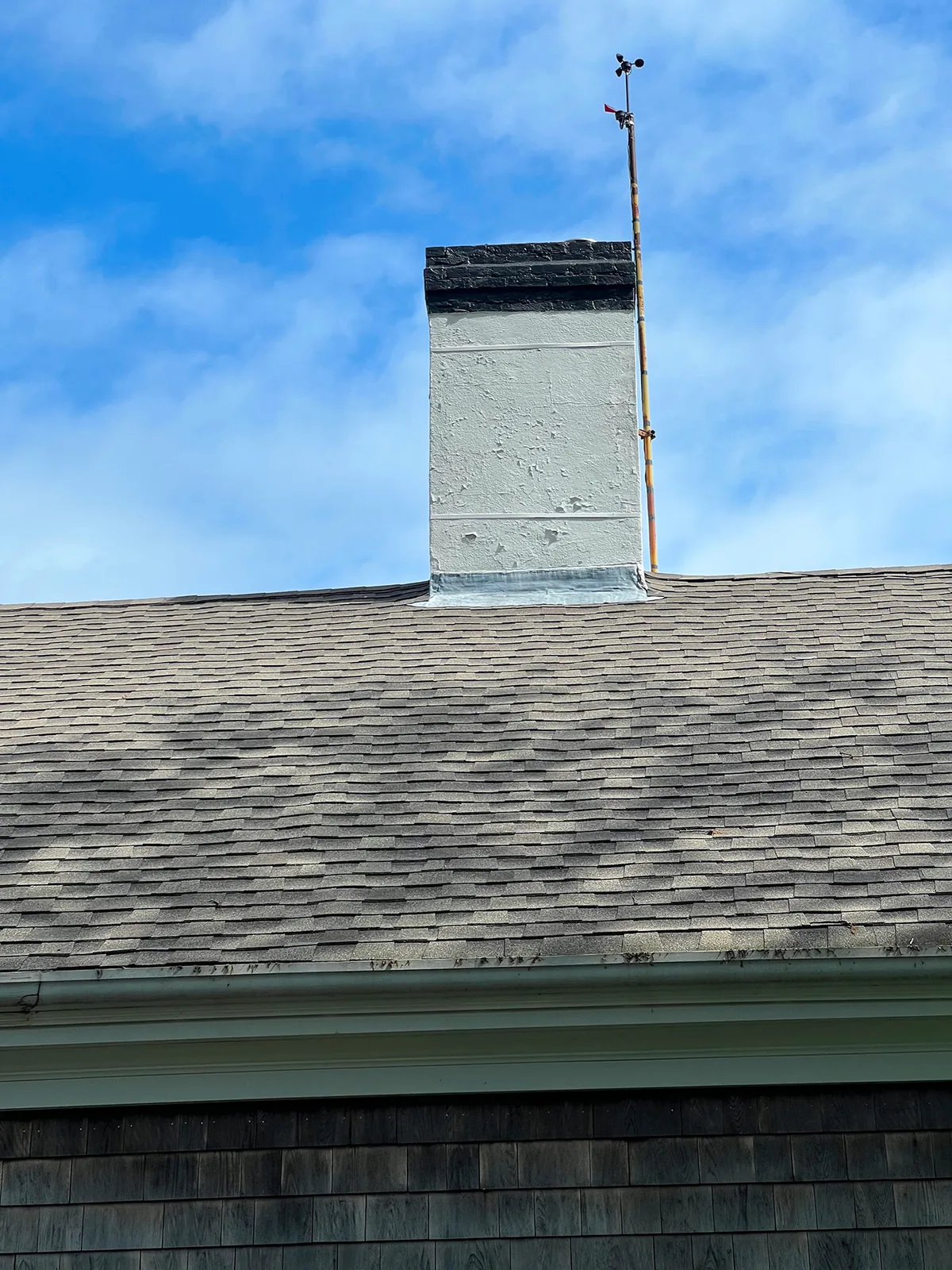A freshly rebuilt chimney crown on a shingled roof