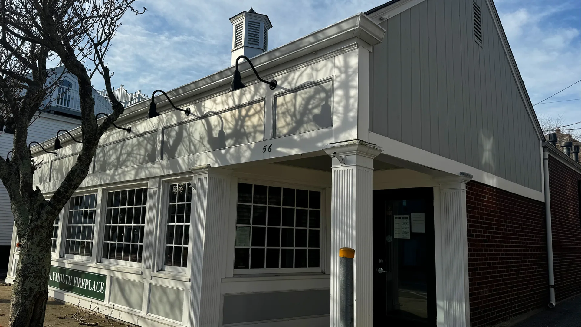 The Plymouth Fireplace storefront at 56 Court Street: white clapboard, fluted pilasters, divided-light windows, and a cupola